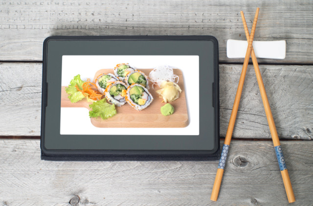 Online Japanese food delivery concept with sushi rolls on an electronic tablet and chopsticks
