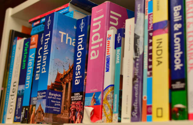 New York, USA - January 11, 2016: Collection of travel guide books consisting of lonely planets for countries in asia and africa on a bookshelf with book of Thailand sticking out